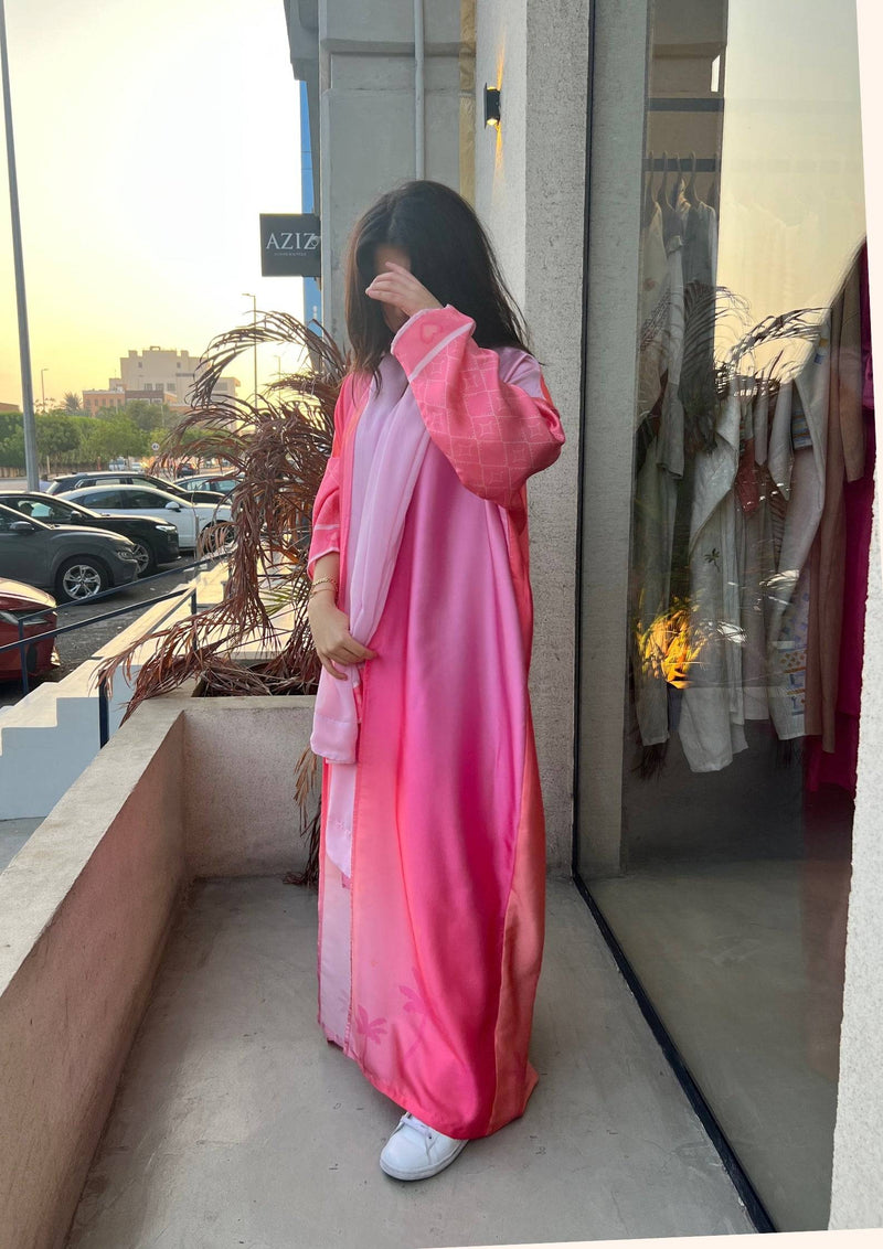 Model in Barbie-Inspired Pink Abaya Set on a balcony, showcasing the ombré pink tones and elegant embroidery details.