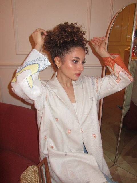 Close-up of model adjusting hair while wearing The Jeddah Horizon - Abaya & Scarf Set, highlighting sleeve artwork.