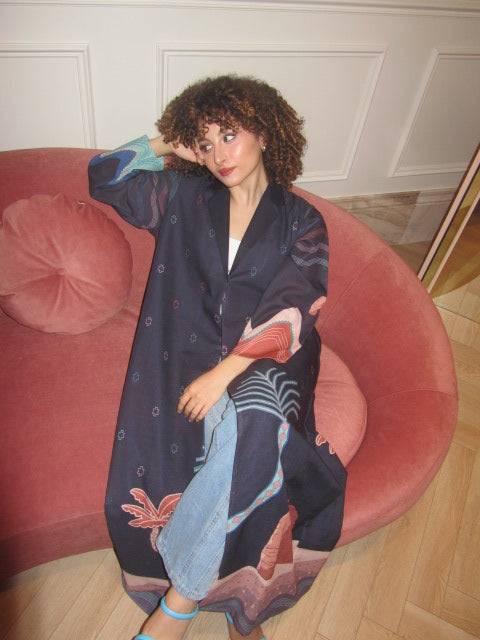Relaxed pose in The Alula Horizon Blazer Abaya, highlighting the garment’s flowing cut and colorful Alula-inspired artwork.