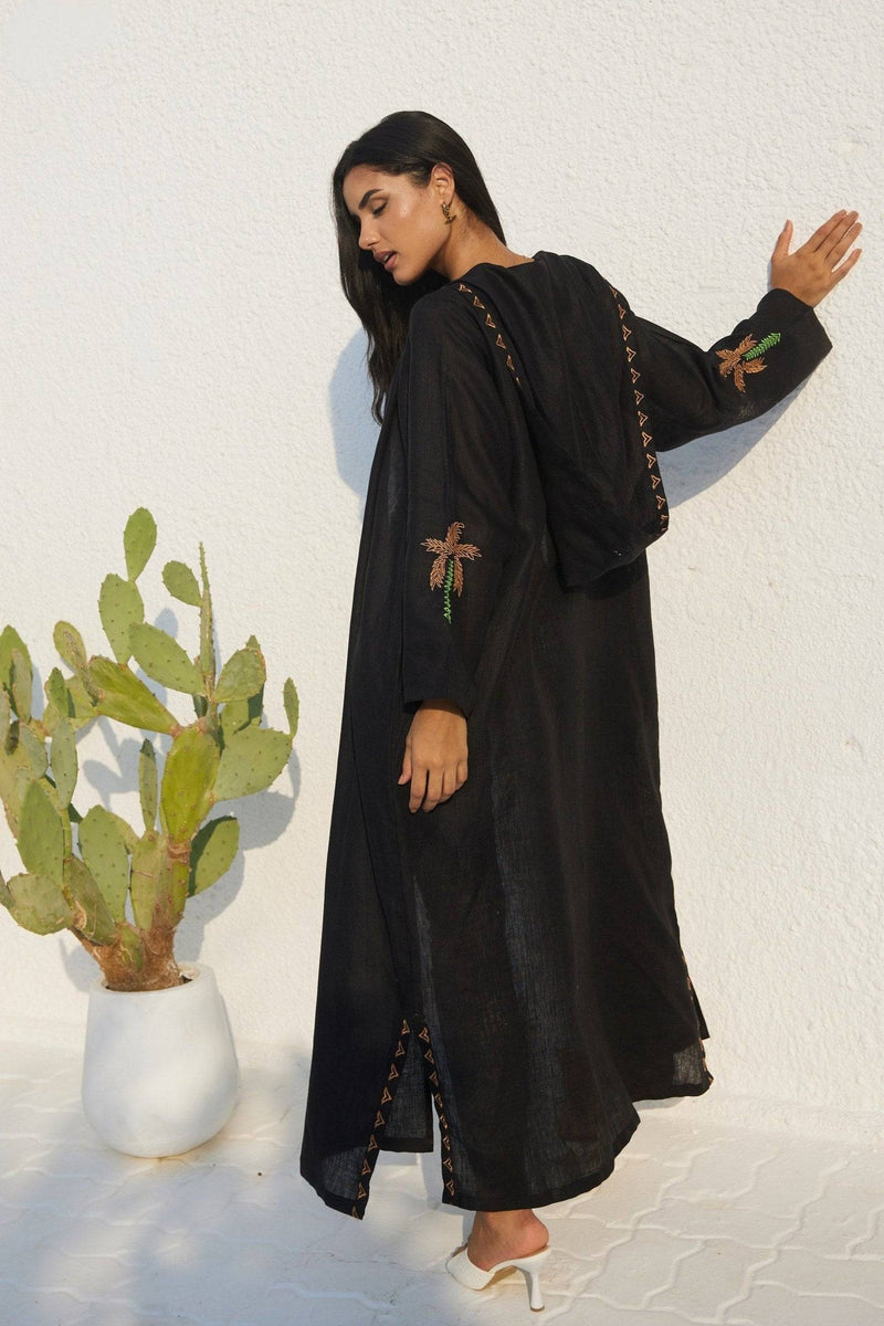 Rear view of Nakhla Hoodie Abaya with hood and palm tree embroidery on sleeves. Organic linen fabric for comfort and style.