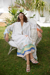 Relaxed model wearing The Jeddah Horizon - Abaya & Scarf Set, showcasing its vibrant hemline and breezy fit in a garden setting.