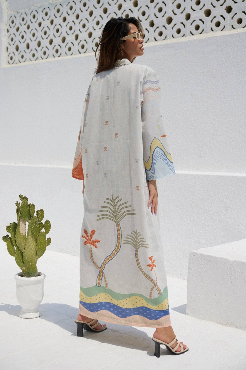 Back view of The Jeddah Horizon - Abaya & Scarf Set featuring palm tree and wave patterns on flowing white fabric.