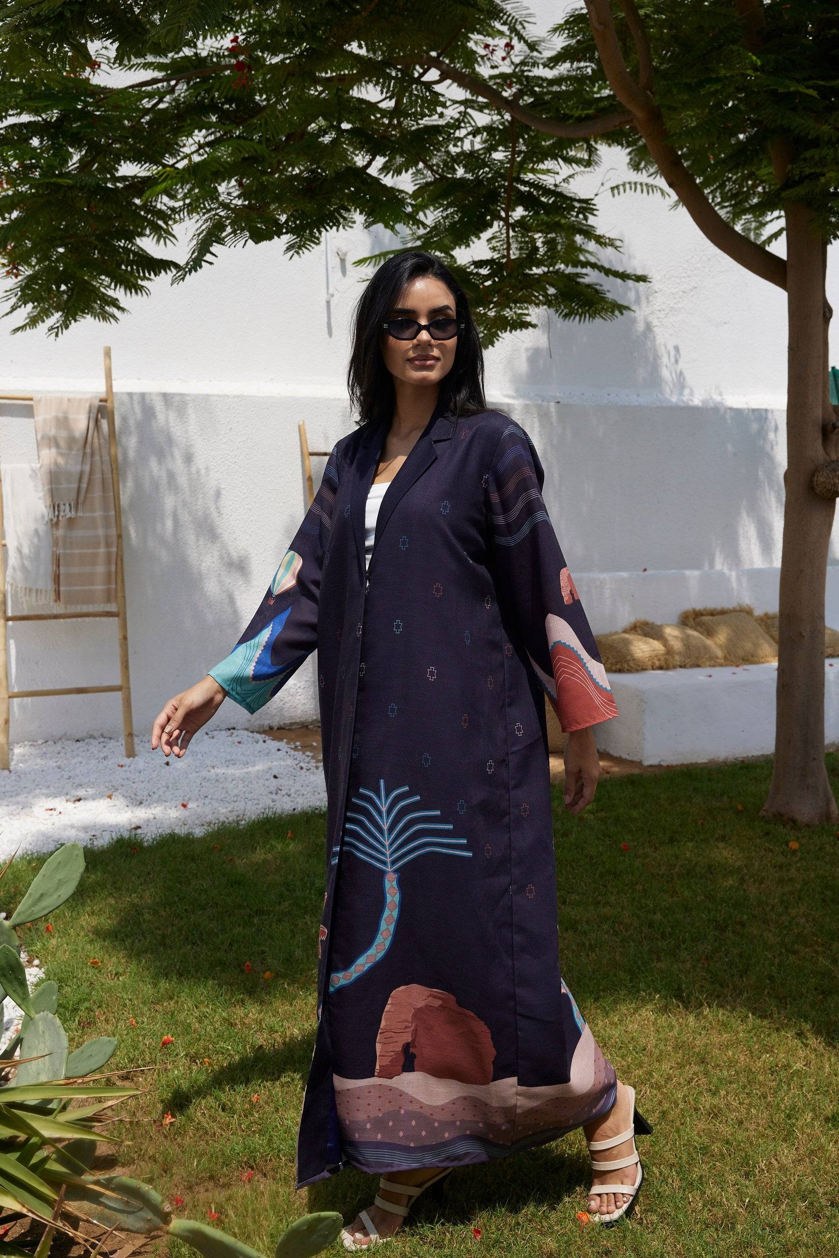 Flowy Alula Horizon Blazer Abaya in motion, showcasing colorful desert and palm tree motifs on sustainable linen fabric.