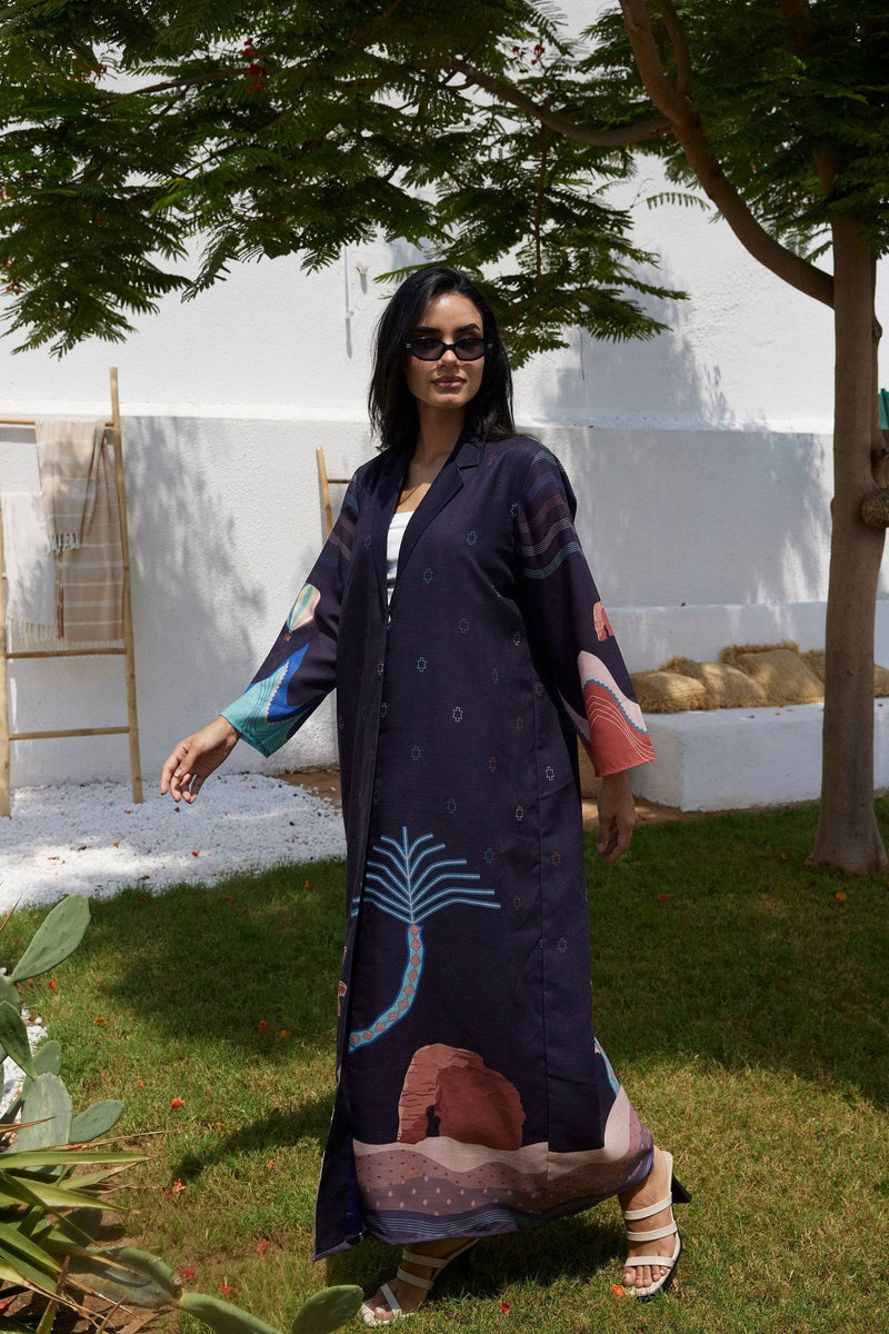 Flowy Alula Horizon Blazer Abaya in motion, showcasing colorful desert and palm tree motifs on sustainable linen fabric.