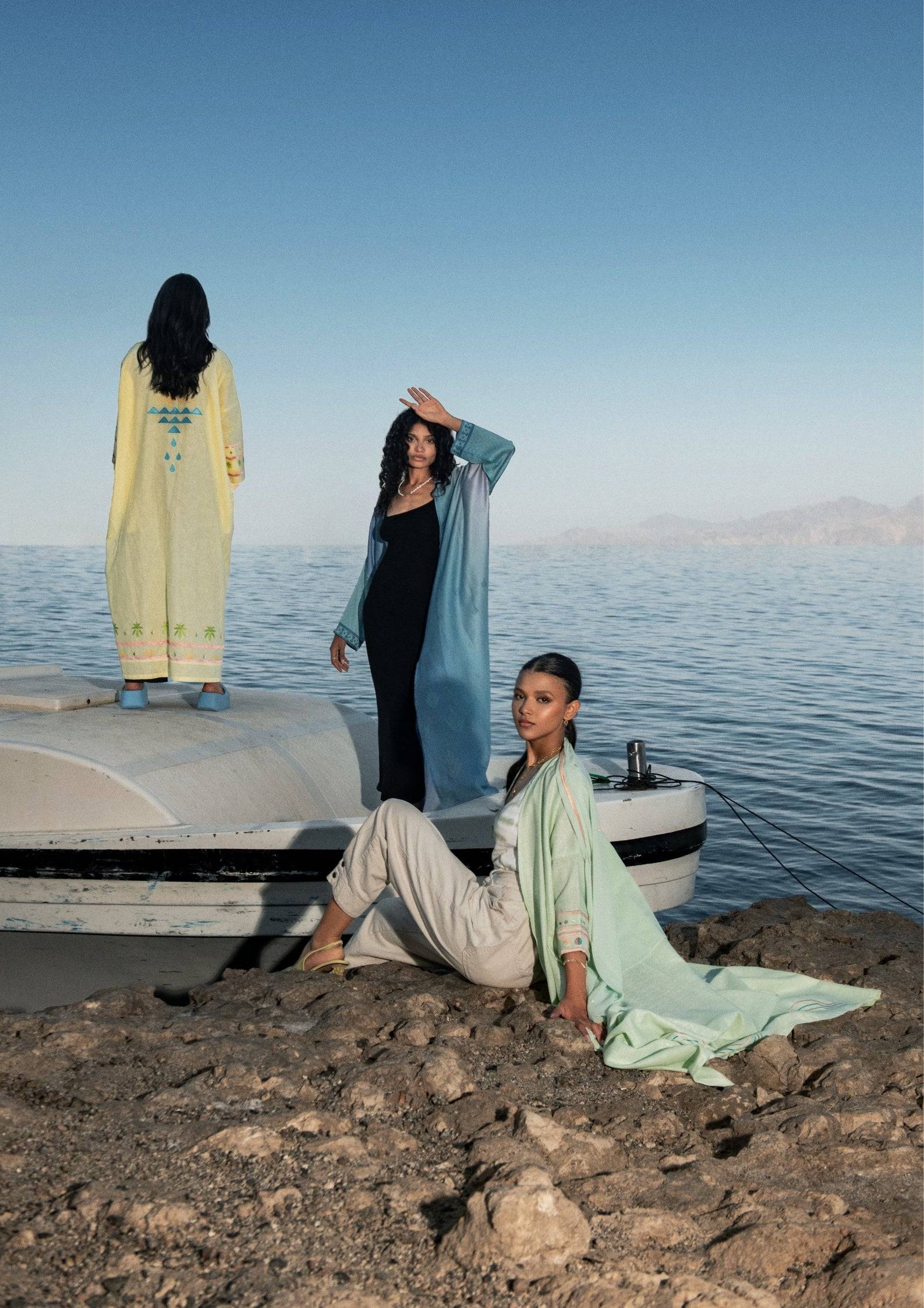Explore the Indigo Dream Ombré Abaya Set in a coastal setting, paired with neutral hues for a timeless, elegant look in traditional summer wear.