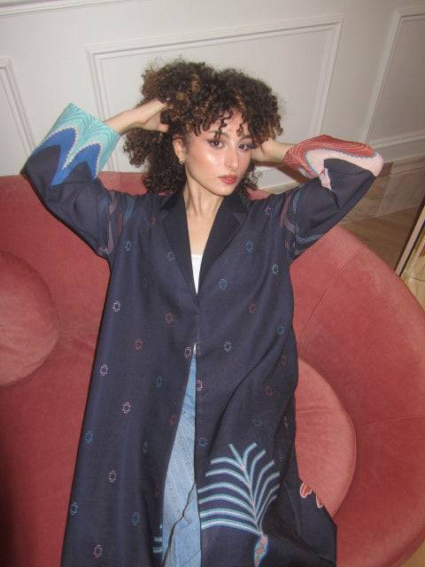 Model in The Alula Horizon Blazer Abaya with hands in hair, showcasing the vibrant sleeve detailing and eco-conscious fabric.