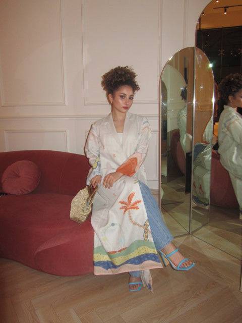 Indoor fashion shot of The Jeddah Horizon - Abaya & Scarf Set, styled with a straw handbag and blue heels.