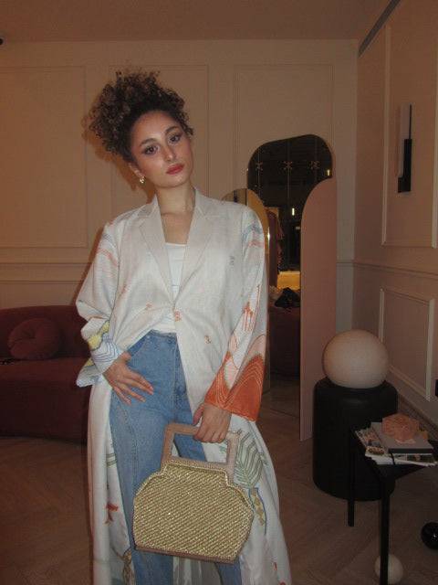 Model seated in The Jeddah Horizon - Abaya & Scarf Set, showcasing vibrant hemline and sleeve prints with casual styling.