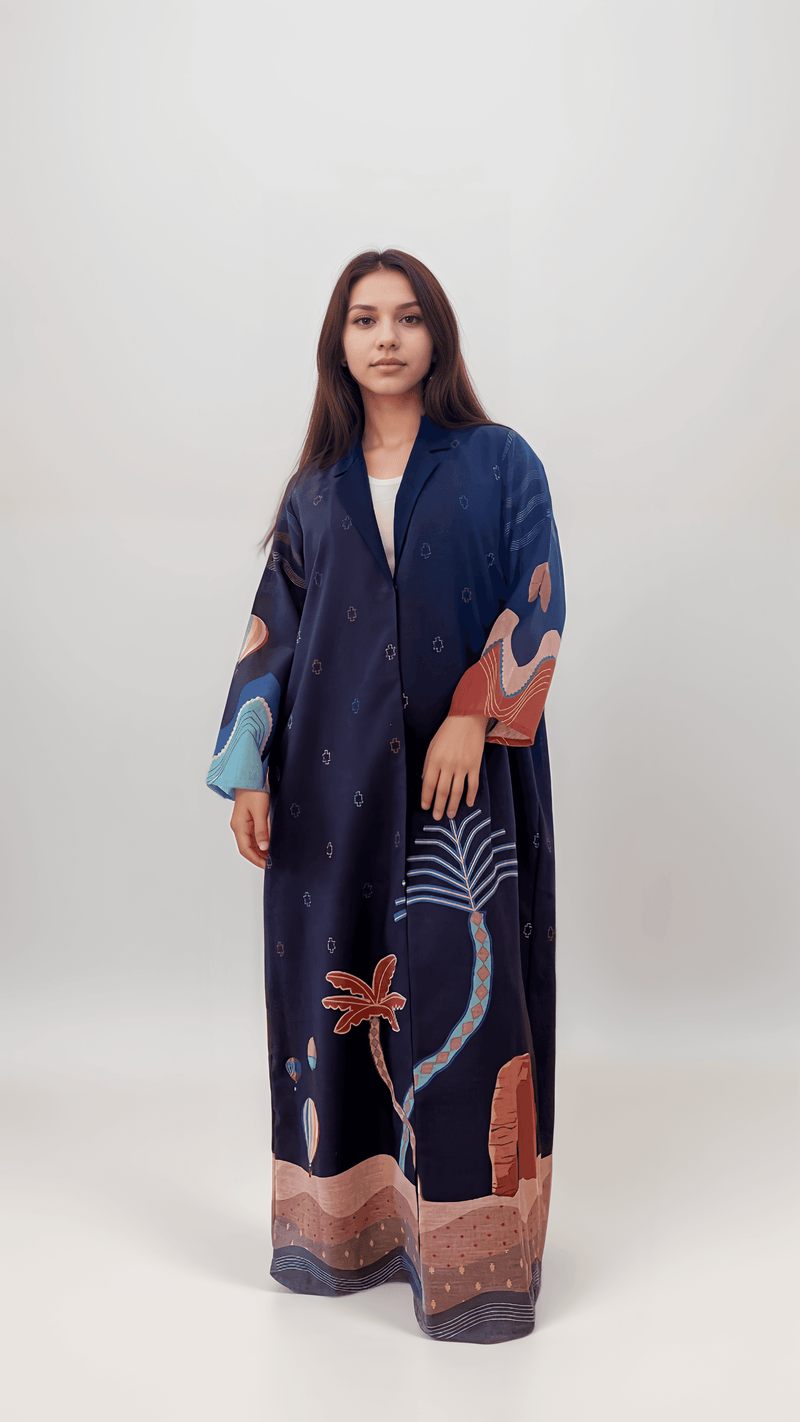 Studio shot of The Alula Horizon Blazer Abaya featuring desert motifs, palm trees, and Elephant Rock on a navy linen base.