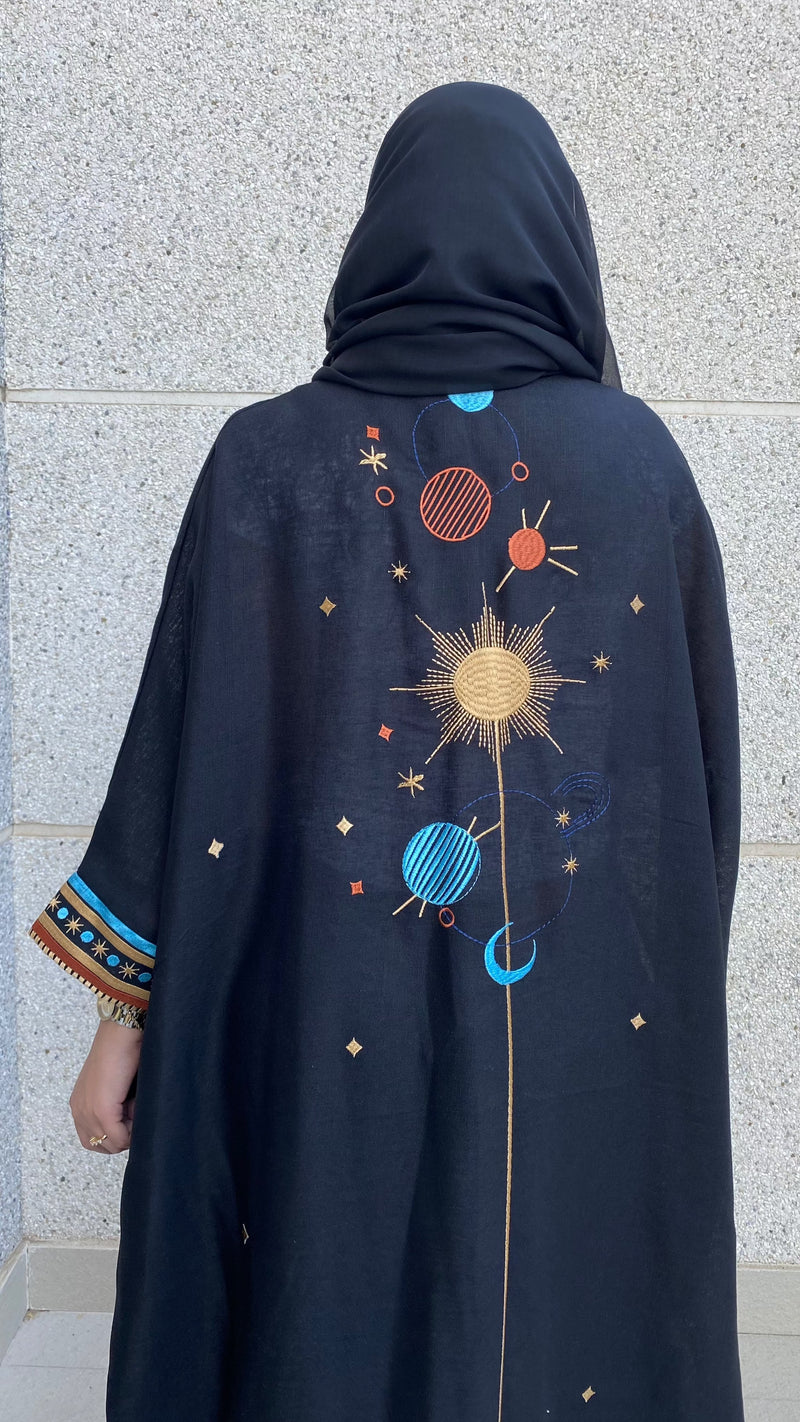 Outdoor view of Distant Galaxies - Show Stopper Back Abaya showcasing vibrant celestial embroidery and modest silhouette for ceremonial fashion.