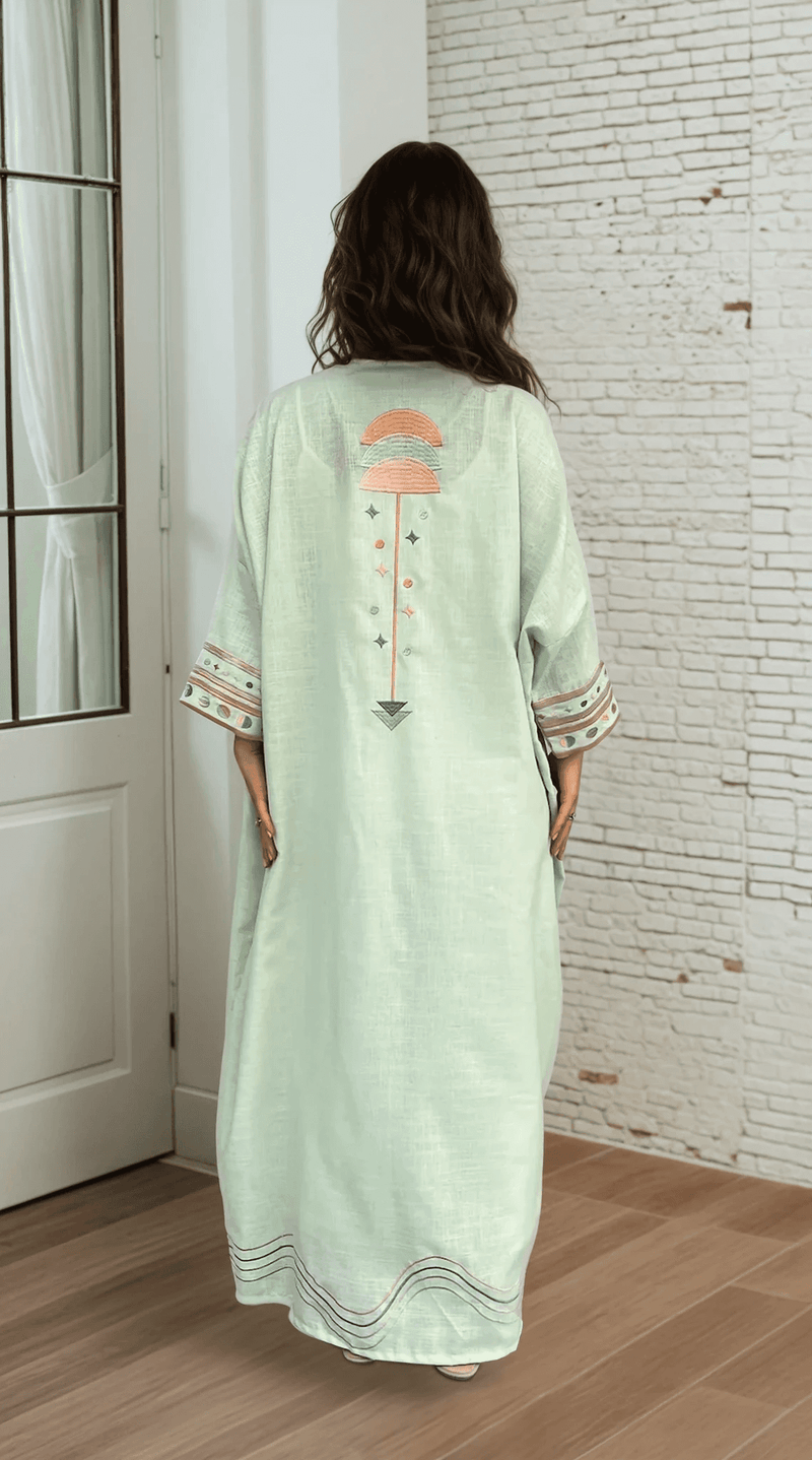 Indoor view of Birthday Abaya & Scarf Set in cold mint, showcasing back embroidery and relaxed traditional silhouette.