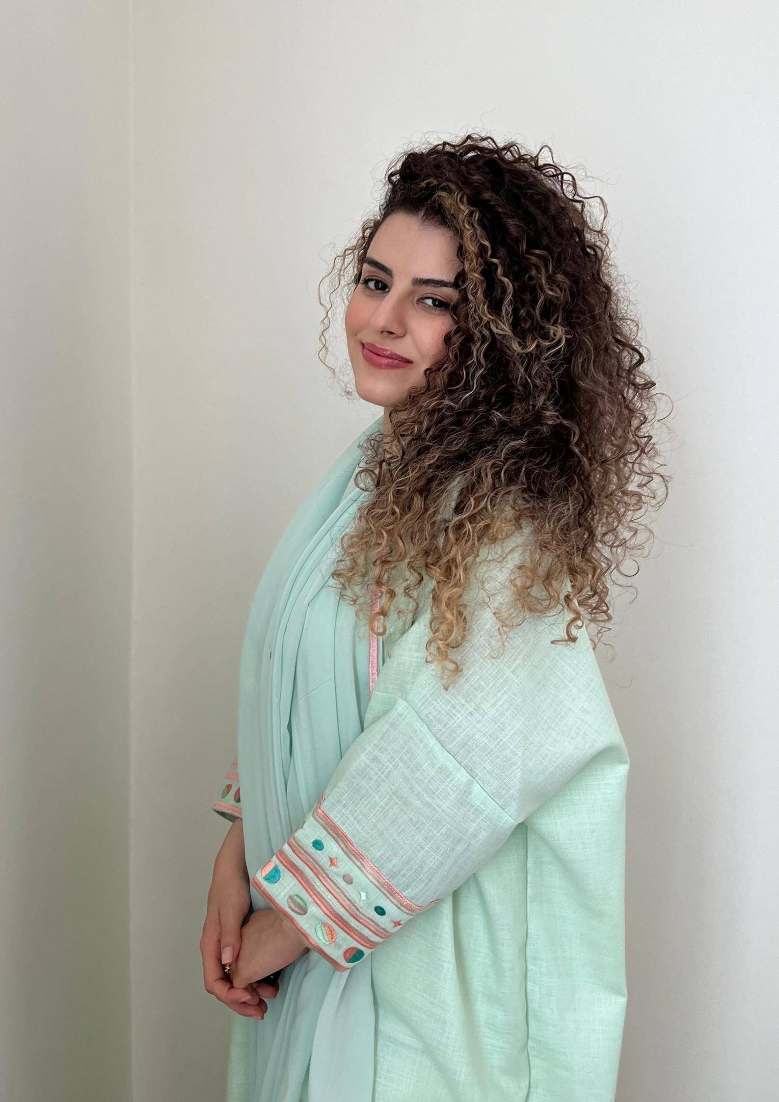 Side profile of model in cold mint Birthday Abaya, highlighting relaxed fit and colorful sleeve embroidery.