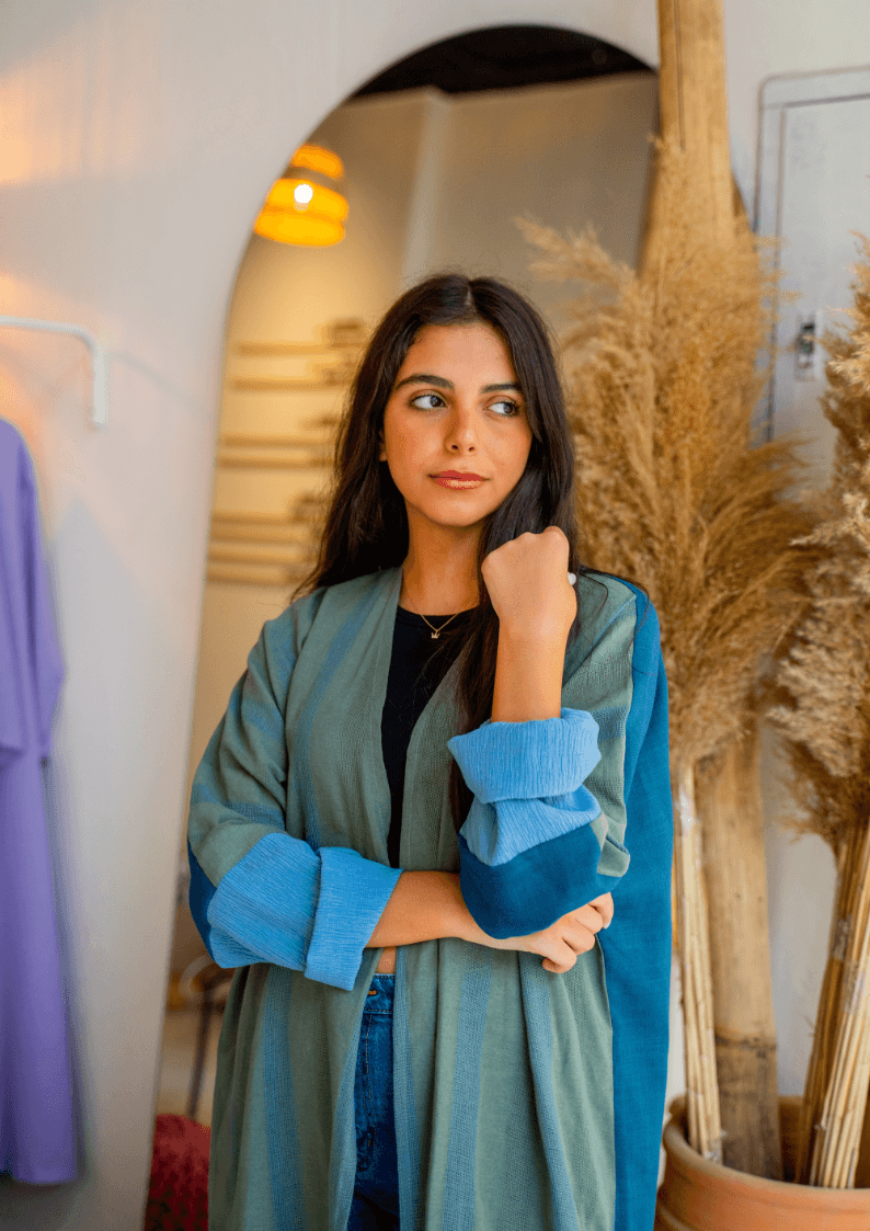 Indoor styling of The WORKaholic Abaya - Daily Wear in green, paired with casual wear for a modern look.