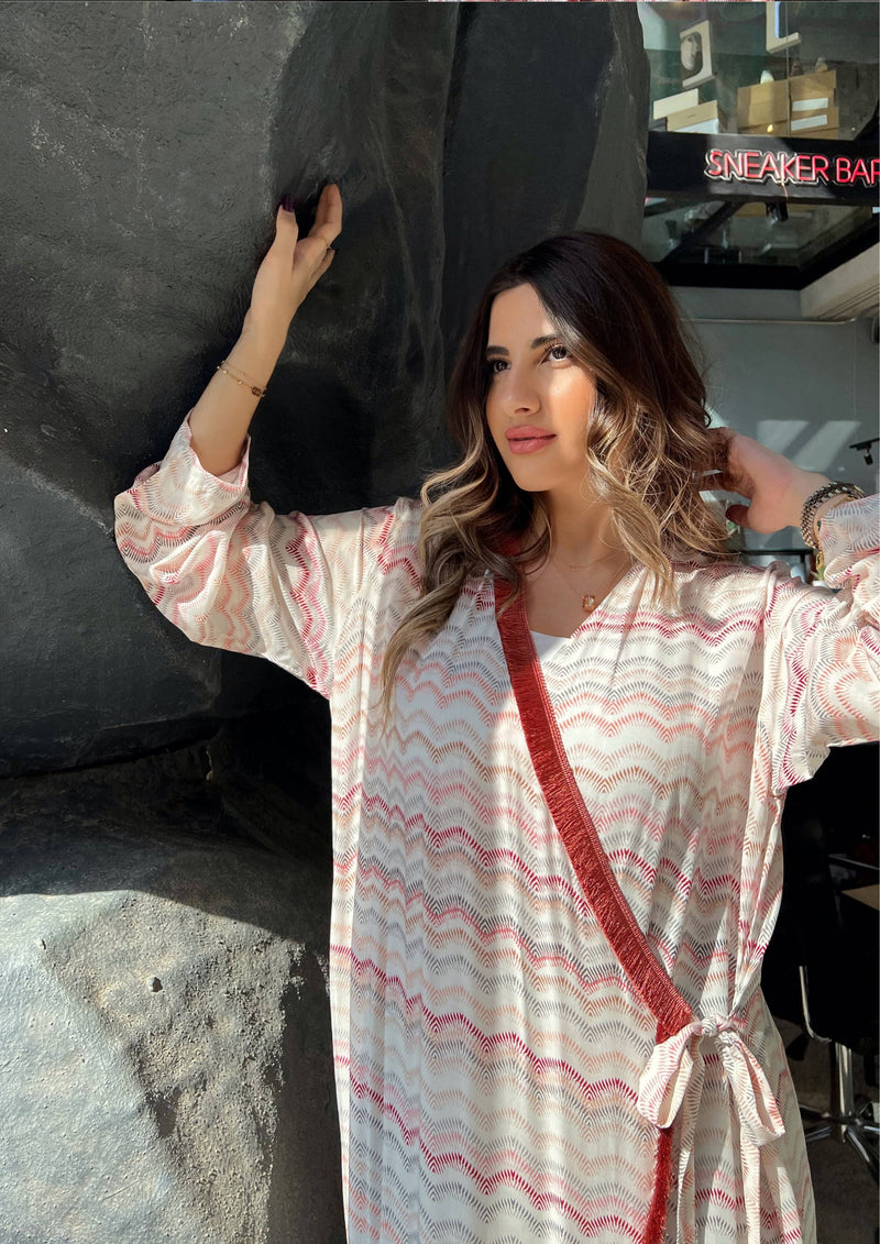 Model posing in pink print soft abaya with red velvet wrap detail. Made in Saudi Arabia, ideal for modest fashion styling.