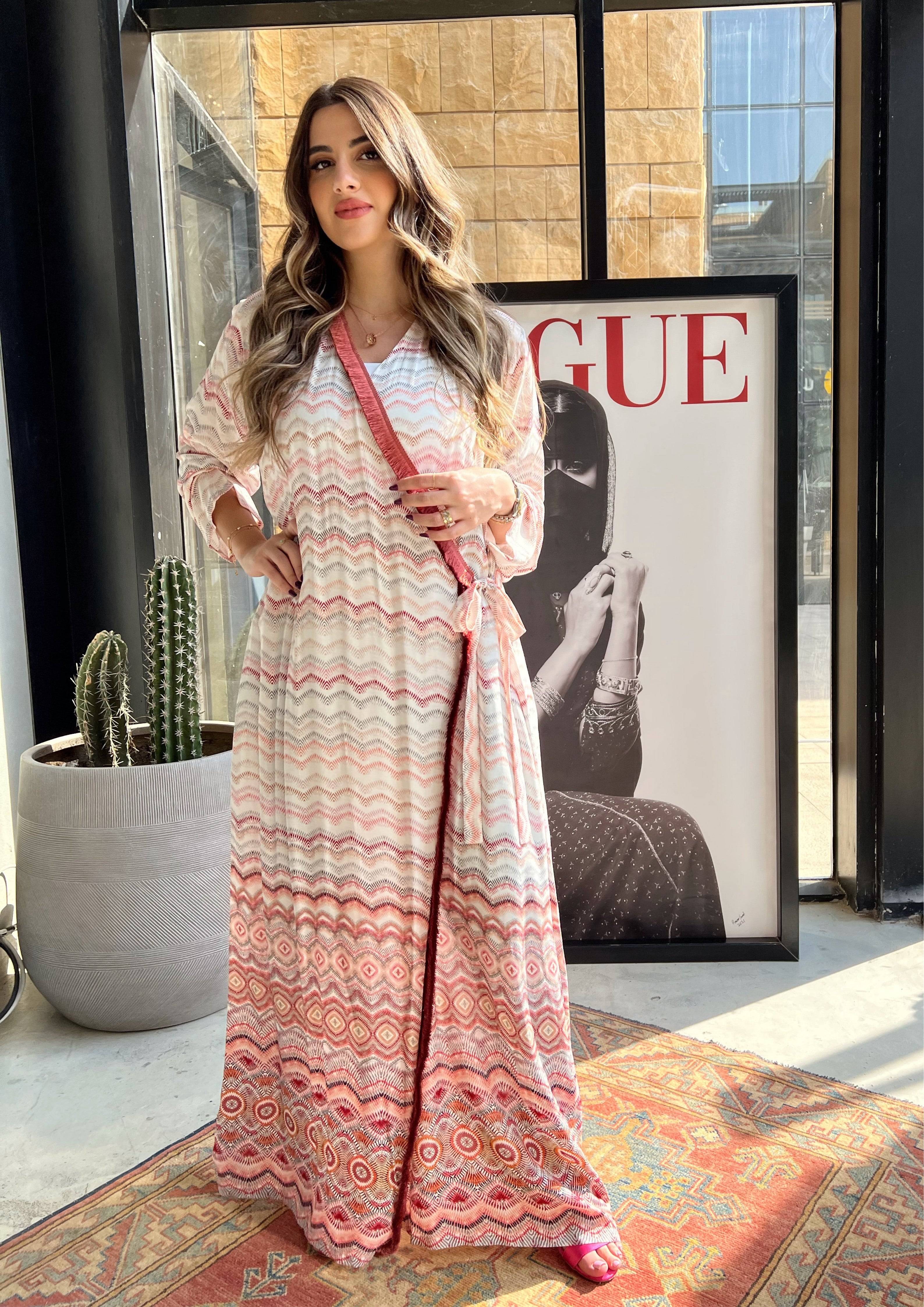 Saudi-made pink print soft abaya with red velvet wrap detail, styled in natural light. Perfect for modest fashion lovers.