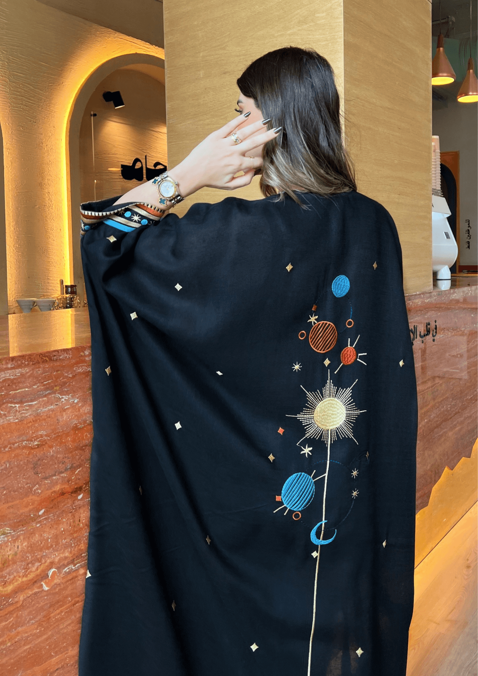 Zoomed-in back embroidery of Distant Galaxies - Show Stopper Back Abaya featuring colorful planets and radiant sunburst design on black fabric.
