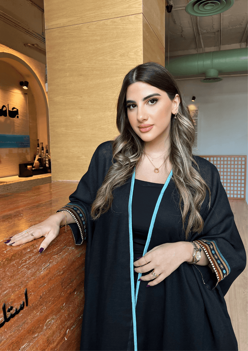 Model wearing Distant Galaxies - Show Stopper Back Abaya with celestial sleeve details and blue trim, styled for a fashionable traditional look.