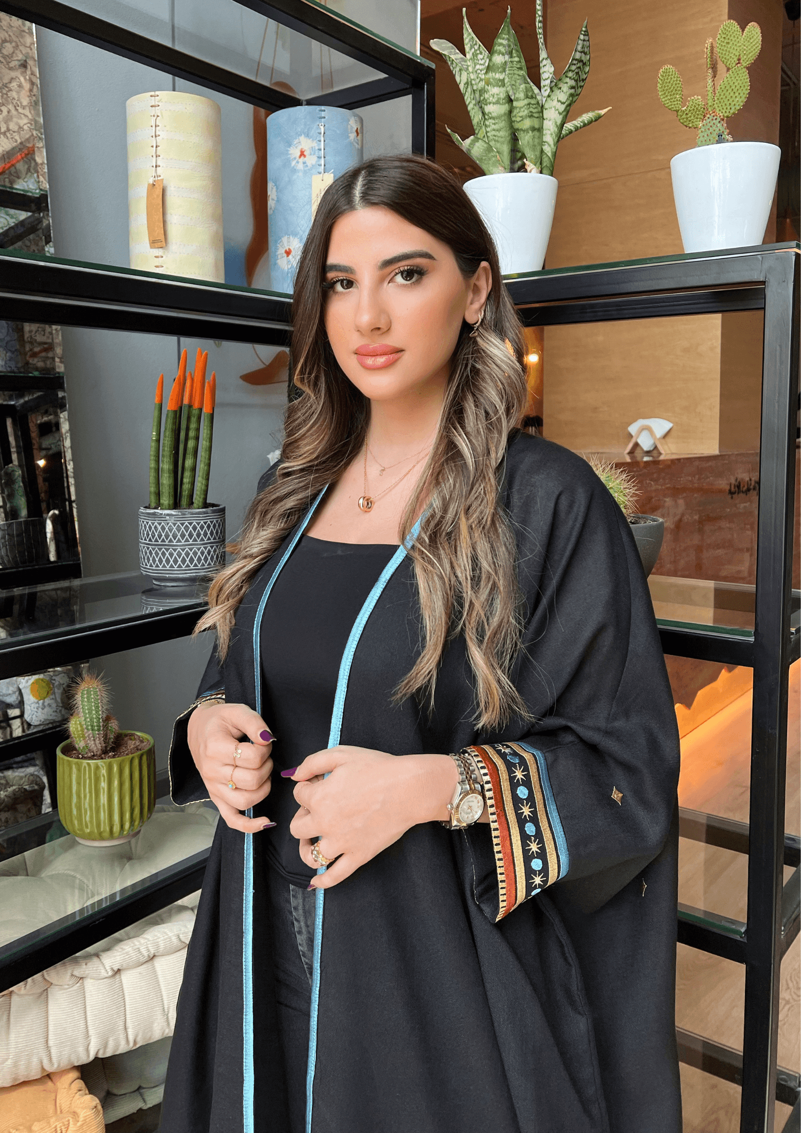 Model in Distant Galaxies - Show Stopper Back Abaya posing indoors with embroidered sleeves and blue trim, styled for modern modest fashion.