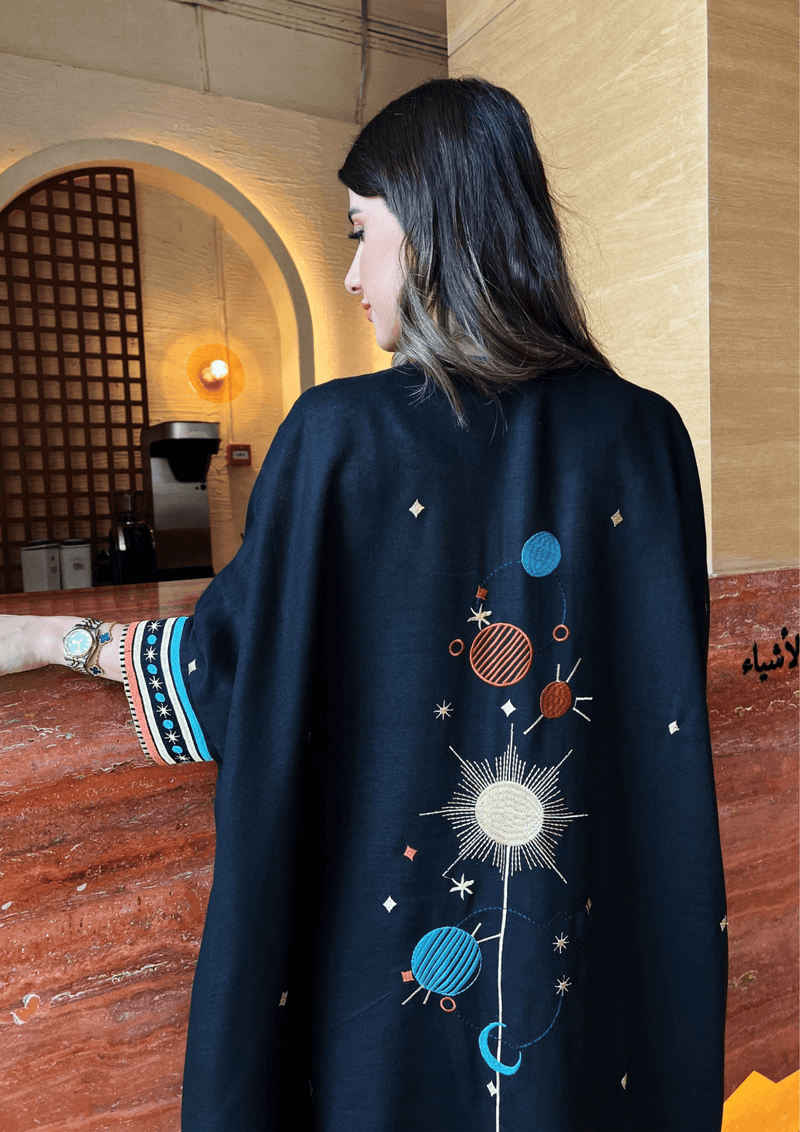Back view of Distant Galaxies - Show Stopper Back Abaya showing detailed galaxy-inspired embroidery with planets and stars in a chic setting.