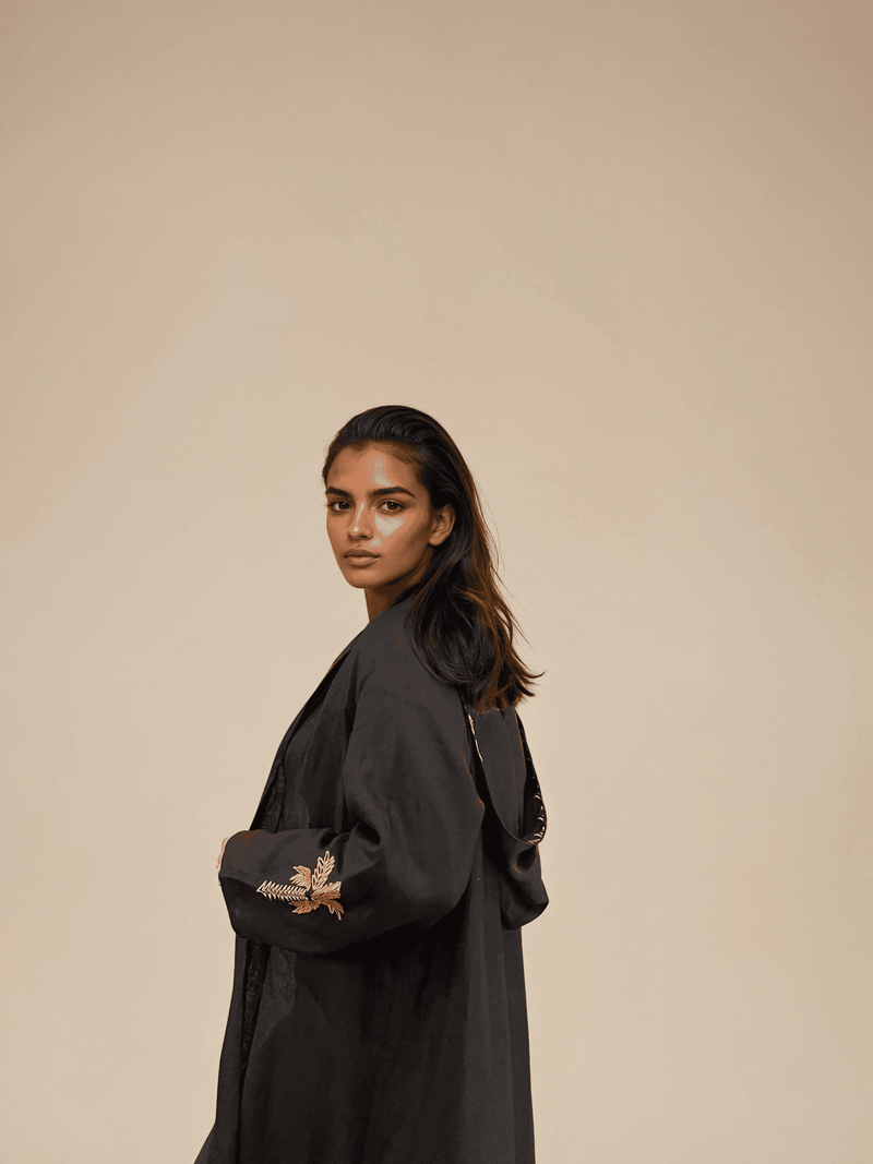 Close-up of Nakhla Hoodie Abaya sleeve showing detailed palm tree embroidery on soft black linen fabric.