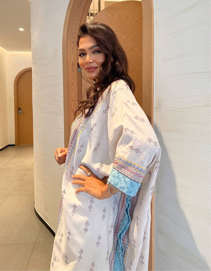 Fatina Abaya styled with soft waves and natural makeup, showcasing the garment's boho embroidery and flowing design.